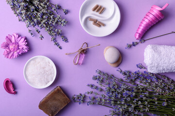 Fototapeta na wymiar Spa massage set with lavender oil on purple background, top view