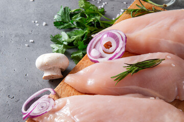 meat , raw chicken fillet with vegetables, onions, herbs, rosemary, parsley and mushrooms on a gray background,