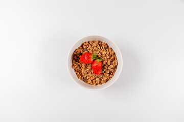 Top view breakfast bowls with granola, milk and organic tasty strawberries in bowl on white background. horizontal space for text