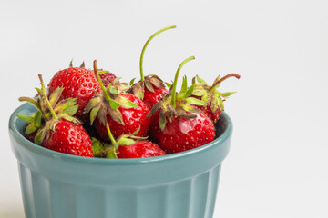 Organic strawberries in green bowl on a white background