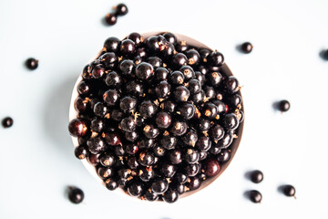 Flat lay composition with organic black currant in a bowl on blue background