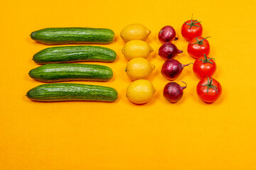 Red tomatoes on a branch and green cucumbers on a white background, top view