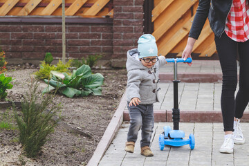 Little boy  with his mother learn to ride a scooter