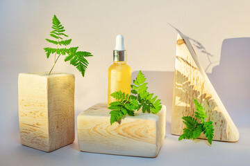 Cosmetic natural oil in a transparent bottle, wooden square and triangular shape. Wood, vegetation...