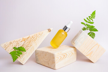 Cosmetic natural oil in a transparent bottle, wooden square and triangular shape. Wood, vegetation...