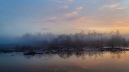 Sunset and forest lake, colorful dawn in the countryside, landscape with reflection in the water and rising fog.