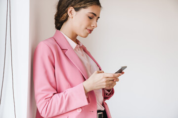 Photo of pleased woman using mobile phone while posing on camera