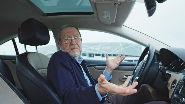 Emotional old handsome businessman shrugging shoulders into camera while reading shock news on smartphone inside parked car. People, technology, transportation. Expressions.