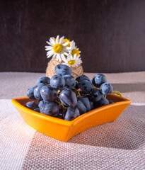 Saucers with black grapes, a bouquet of flowers on the table