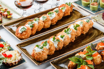 Delicious appetizers with deep fried meat with sauce and herbs on plate over banquet table. Catering food, canape and snacks, close up