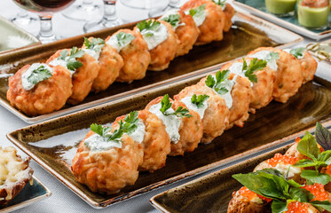 Delicious appetizers with deep fried meat with sauce and herbs on plate over banquet table. Catering food, canape and snacks, close up