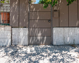 family house entrance metallic brown door and fence by the sidewalk