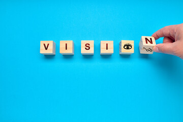 Man turning a die of the word VISION on a blue background