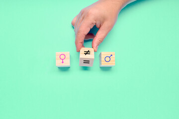 Hand turns a dice and changes a unequal sign to a equal sign between symbols of men and women