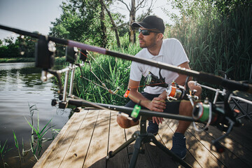 Young fisherman fishing on lake or river. Serious concentrated professional adult guy sitting in...