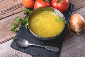 Chicken soup bouillon in a bowl on rustic wooden table