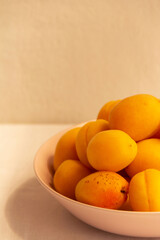 apricots in a plate on a light background in the morning light-