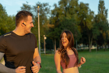 Fototapeta premium Young couple running i park, talking and joking together.