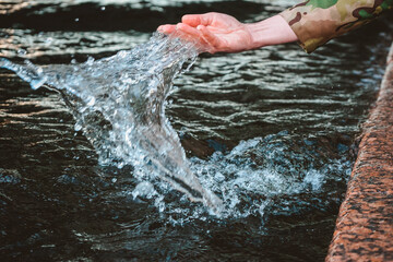 The Girl's hand surging water and drops and splashes fly. Touching the river with the palm of your hand while walking along the embankment