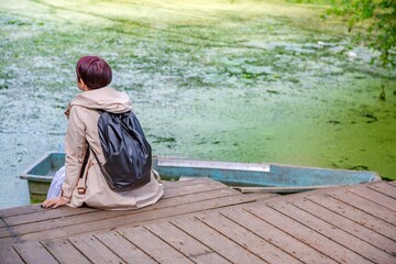 Young caucasian girl has a rest near an old abandoned pond with duckweed