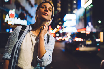 Young female tourist looking for taxi standing on busy Times square illuminated with lights at...