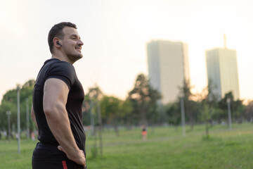 Fototapeta na wymiar Attractive Man standing in a park after jogging.