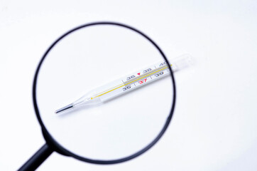 Mercury thermometer on a white background view through a magnifying glass. 36.6 temperature on a thermometer