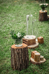 
A floral arrangement in rustic style, decorated with logs, glass vases and candles.