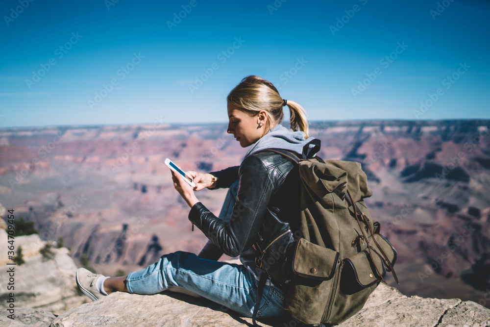Aufkleber young female tourist satisfied with mobile data network in mountains sending message on telephone re