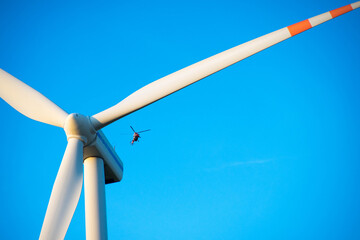 Przelatujący helikopter kolo turbiny wiatrowej - obrazy, fototapety, plakaty