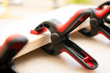 Plastic spring clamps are clamping to glue two pieces of wood