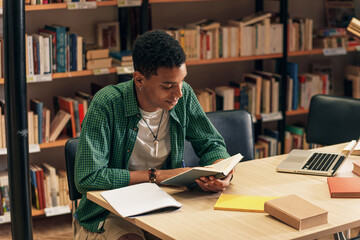 Young male student study in the library reading book.