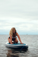 Woman practicing yoga on the paddle board in the morning