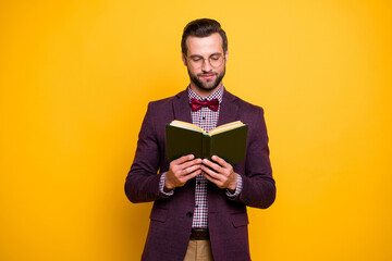 Portrait of his he nice attractive focused intelligent guy reading interesting book academic learning hobby isolated over bright vivid shine vibrant yellow color background