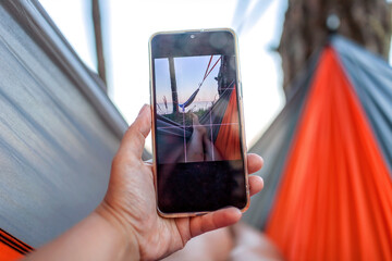 Local vacation. Woman having rest in hammock on the bank of the sea and making selfie