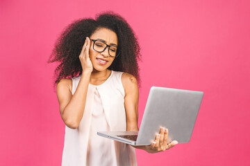 Young african american black sad tired cool lady with curly hair using laptop isolated over pink background.