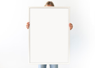 Painting frame mockup. Woman holds a big vertical white picture frame. Copy space for your logo