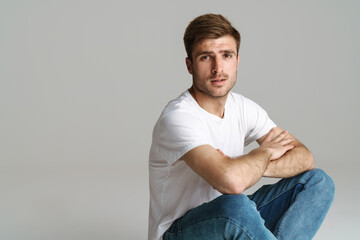Portrait of redhead man looking at camera while sitting on floor