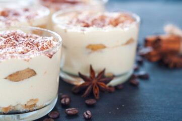 exquisite tiramisu in glasses decorated with cocoa powder on a dark background