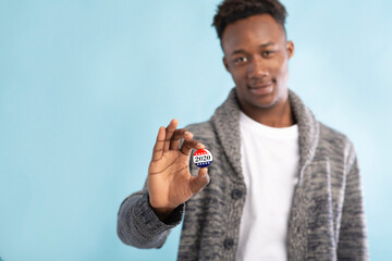 African american voter with vote button in hand on blurred background