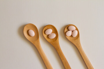 Assorted pharmaceutical medicine. Dosage. Tablets and capsules on a wooden spoon on a white background. Concept of medicine. Alternative homeopathy. Flatley. The view from the top. 