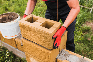 Hard work of a builder - a professional bricklayer skillfully builds walls of brick and concrete block