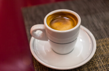 Close up beautiful white coffee cup with foam of morning, breakfast espresso with latte art on the black vintage red table Dark black and white space background Trendy toning Hot Latte Art coffee