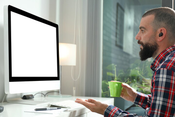 Young man working from home in front of computer with blank screen