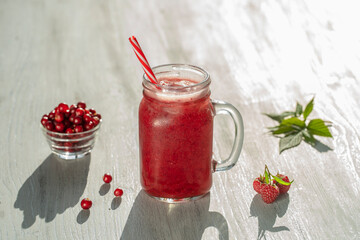 Fresh organic red smoothie in glass mug on white table, close up. Refreshing summer fruit drink. The concept of healthy eating. Cranberry and raspberry smoothie