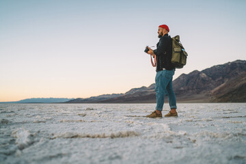 Bearded guy with camera exploring wild lands of arid environment in Badwater national park, male...