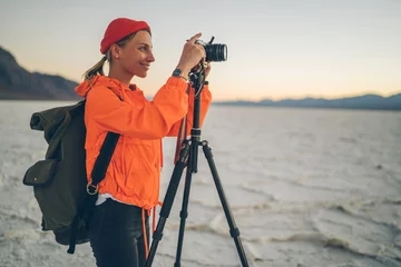 Fotobehang Smiling female photographer making pictures of natural landscape of Badwater basin enjoying expedition,woman using tripod and digital camera shooting scenic view of wild area of Death valley. © BullRun
