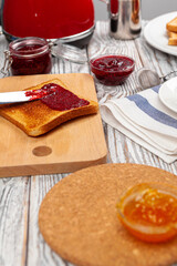 Photo of kitchen table with toasts, fruit jams and knife