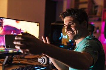 Image of man gesturing peace sign and taking selfie photo on cellphone