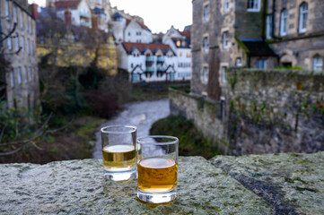Scotch single malts or blended whisky spirits in glasses with old houses of Edinburgh on...